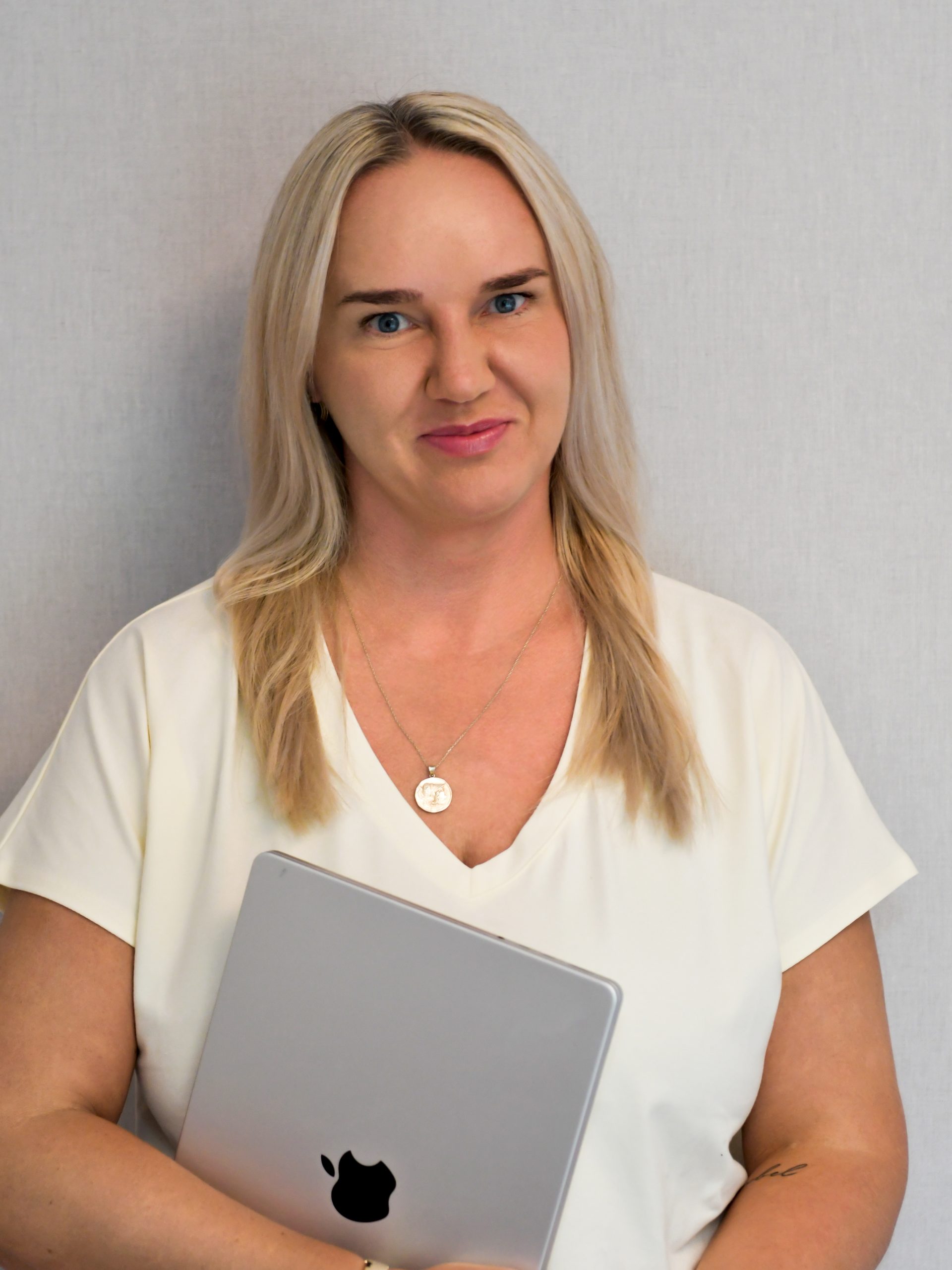 Kasia Kraszewska - Uśmiechnięta kobieta z długimi blond włosami trzymająca zamknięty laptop.