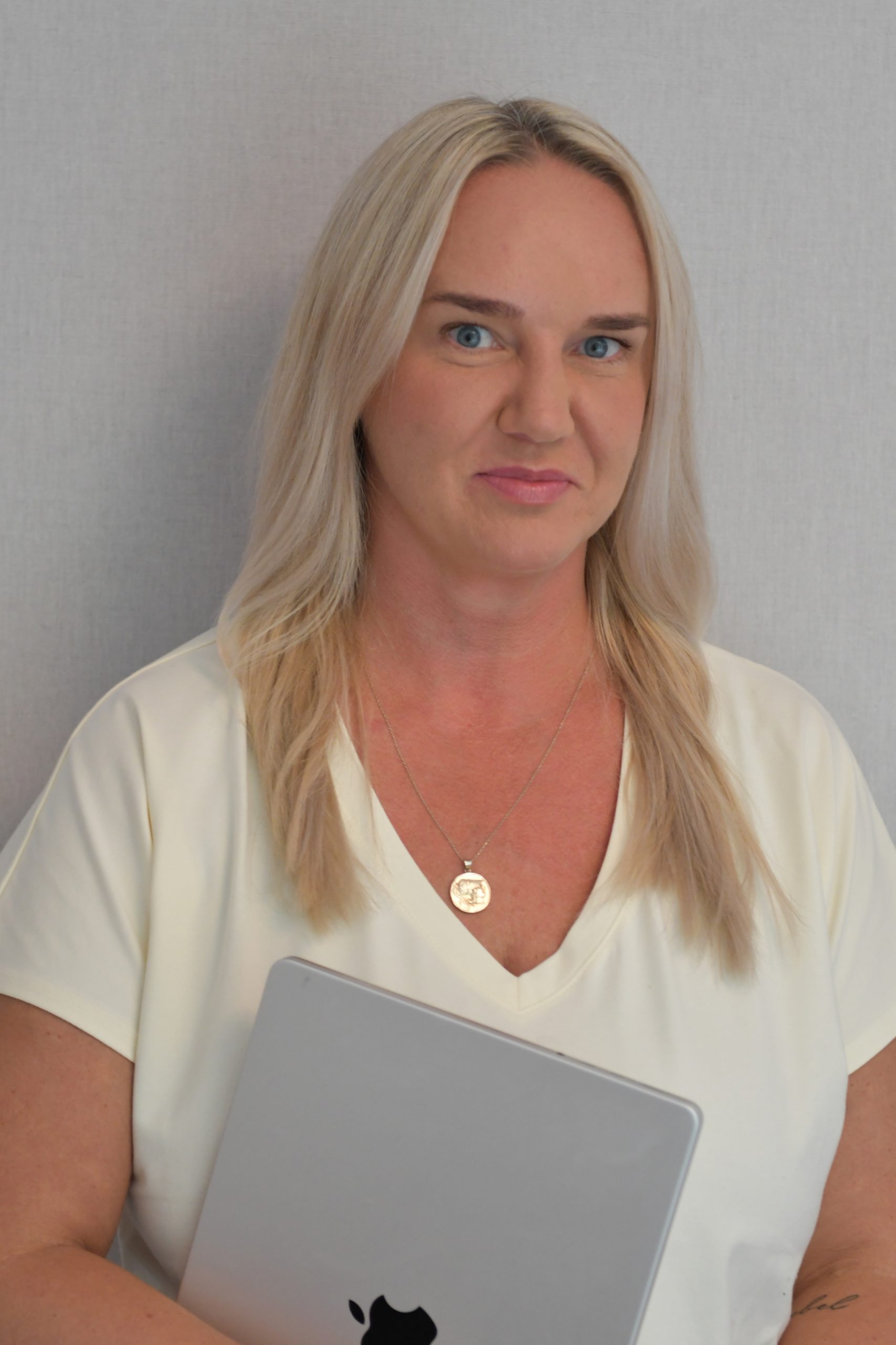 Kasia Kraszewska - Uśmiechnięta kobieta z długimi blond włosami trzymająca zamknięty laptop.